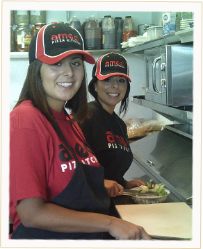 Two Team Members Making Pizzas in our World Famous Kitchen.