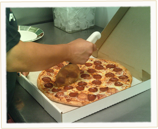 Our Ameci's Pepperoni Pizza being cut into delicious slices.